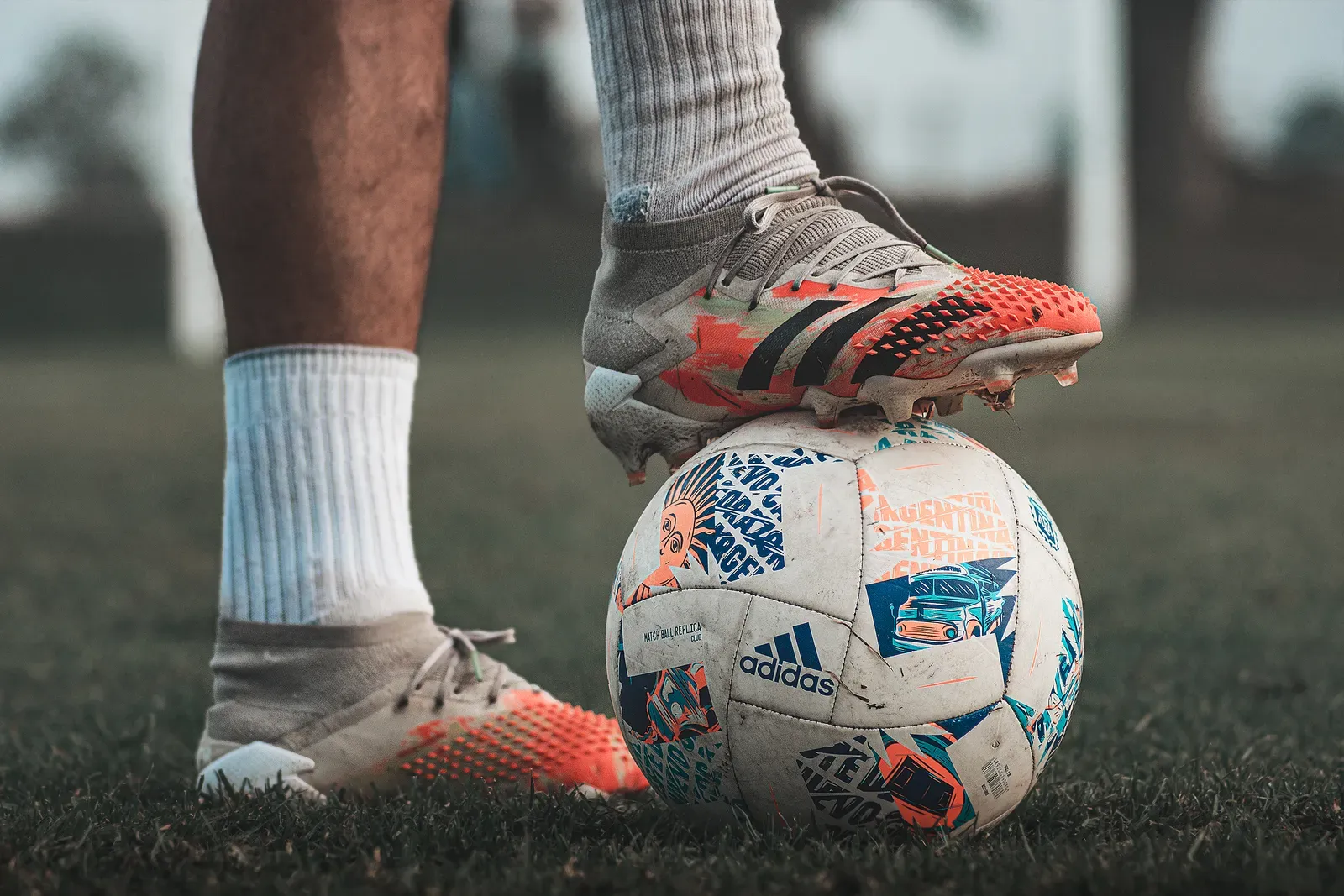 Soccer cleats resting on a ball on grass