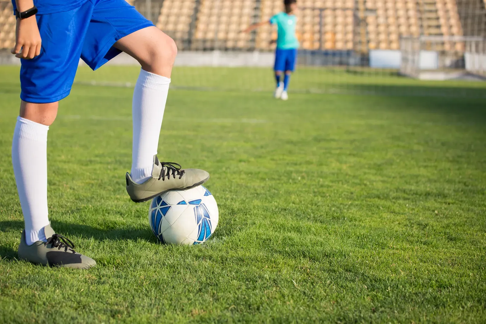 A player in blue socks controlling a soccer ball